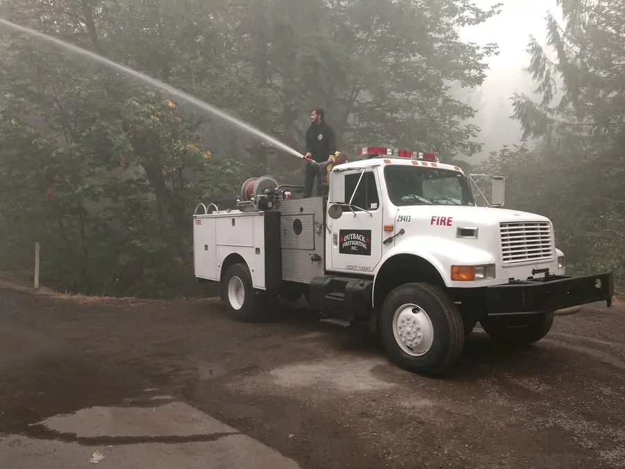 Outback fire engine spraying water in a smoky forest